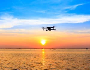 Drone flying over the ocean with a sunset background